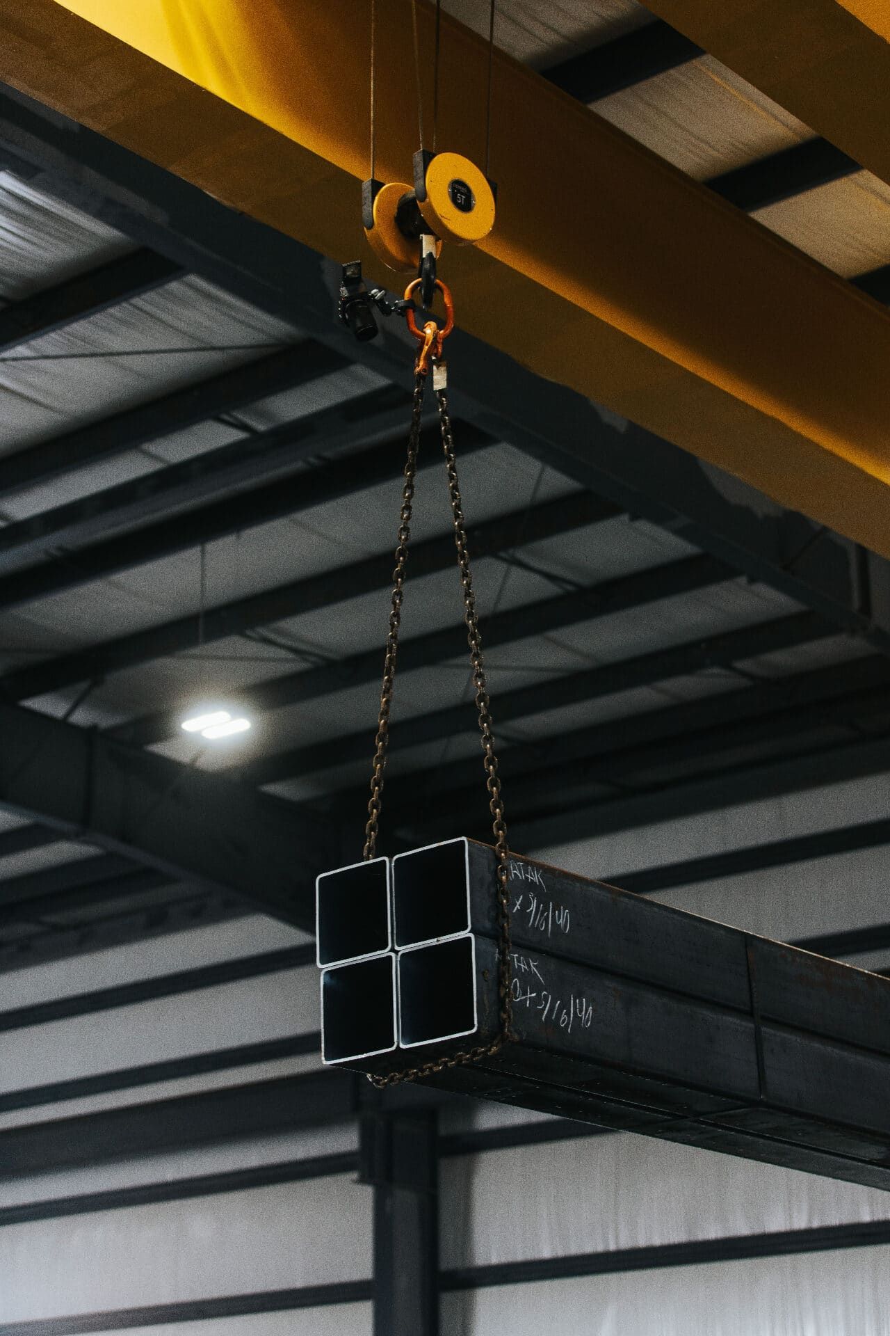 Overhead crane lifting tube steel inside the Brown Strauss Houston facility