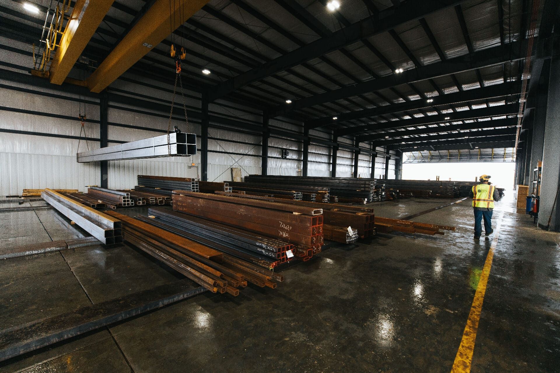 Overhead crane lifting a beam of square steel tubing inside the Brown Strauss warehouse