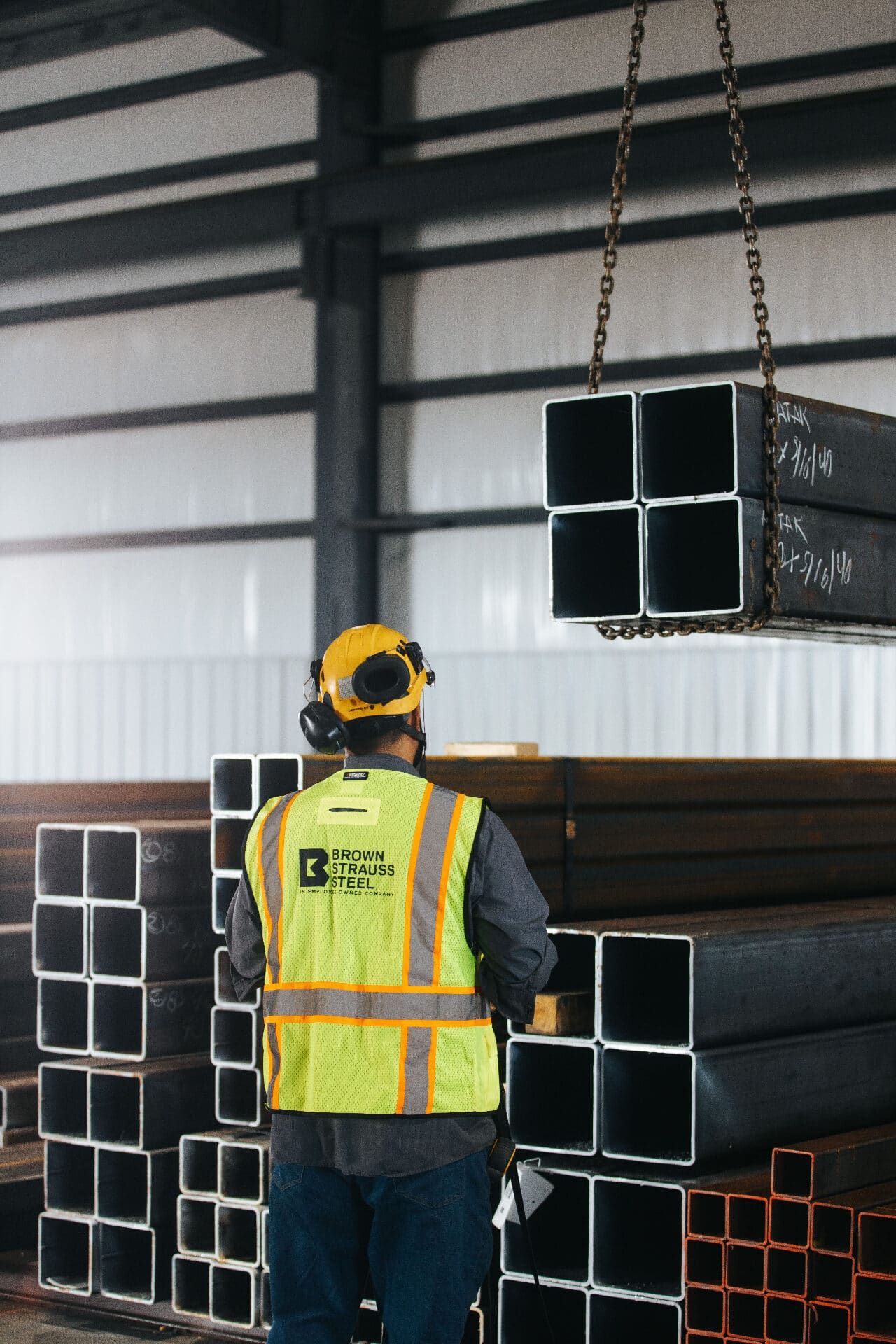 Brown Strauss Steel team member guiding suspended steel tubing in the facility