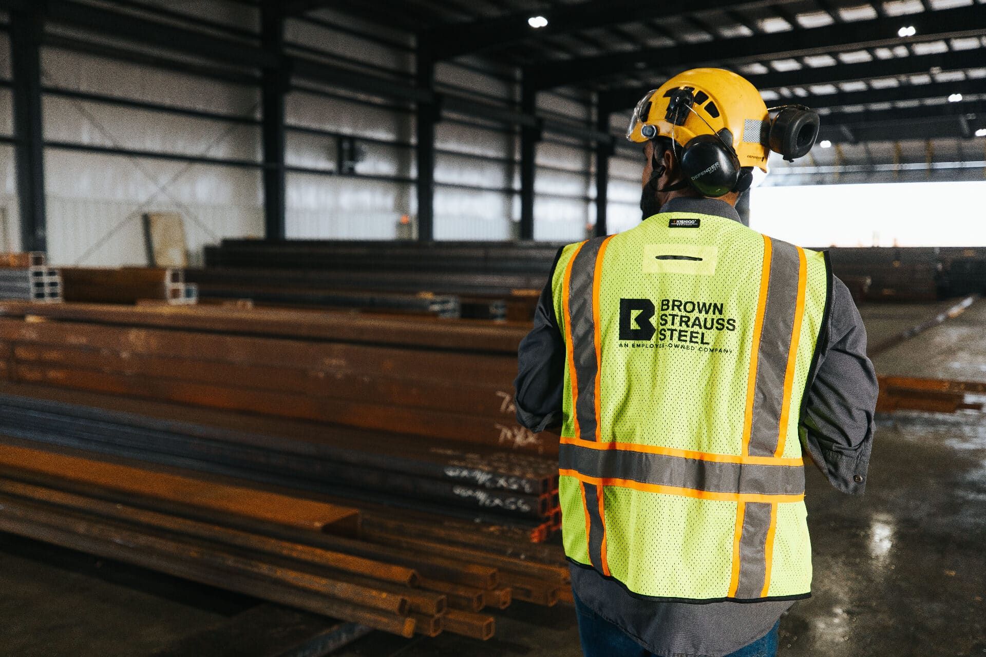Brown Strauss Steel team member in branded vest walking the warehouse floor
