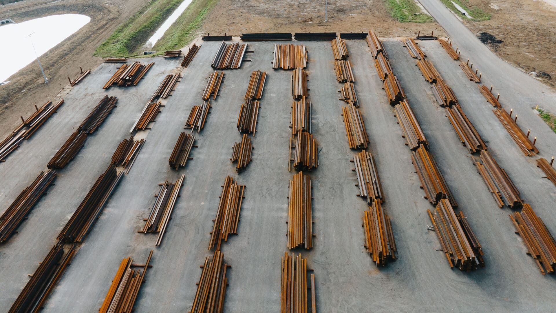 Top-down aerial of organized steel stacks in the Brown Strauss yard