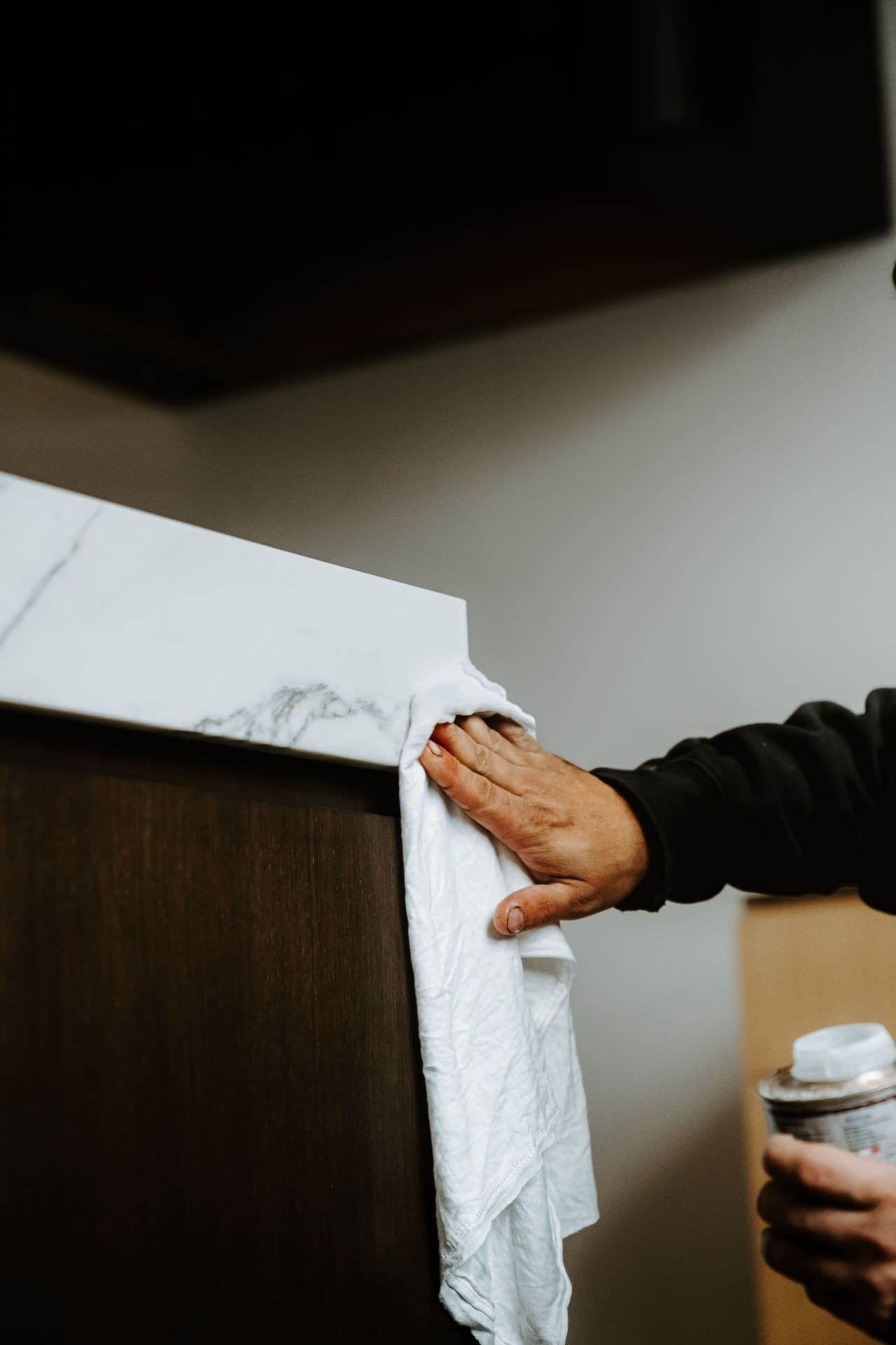 Hand wiping marble countertop edge during install
