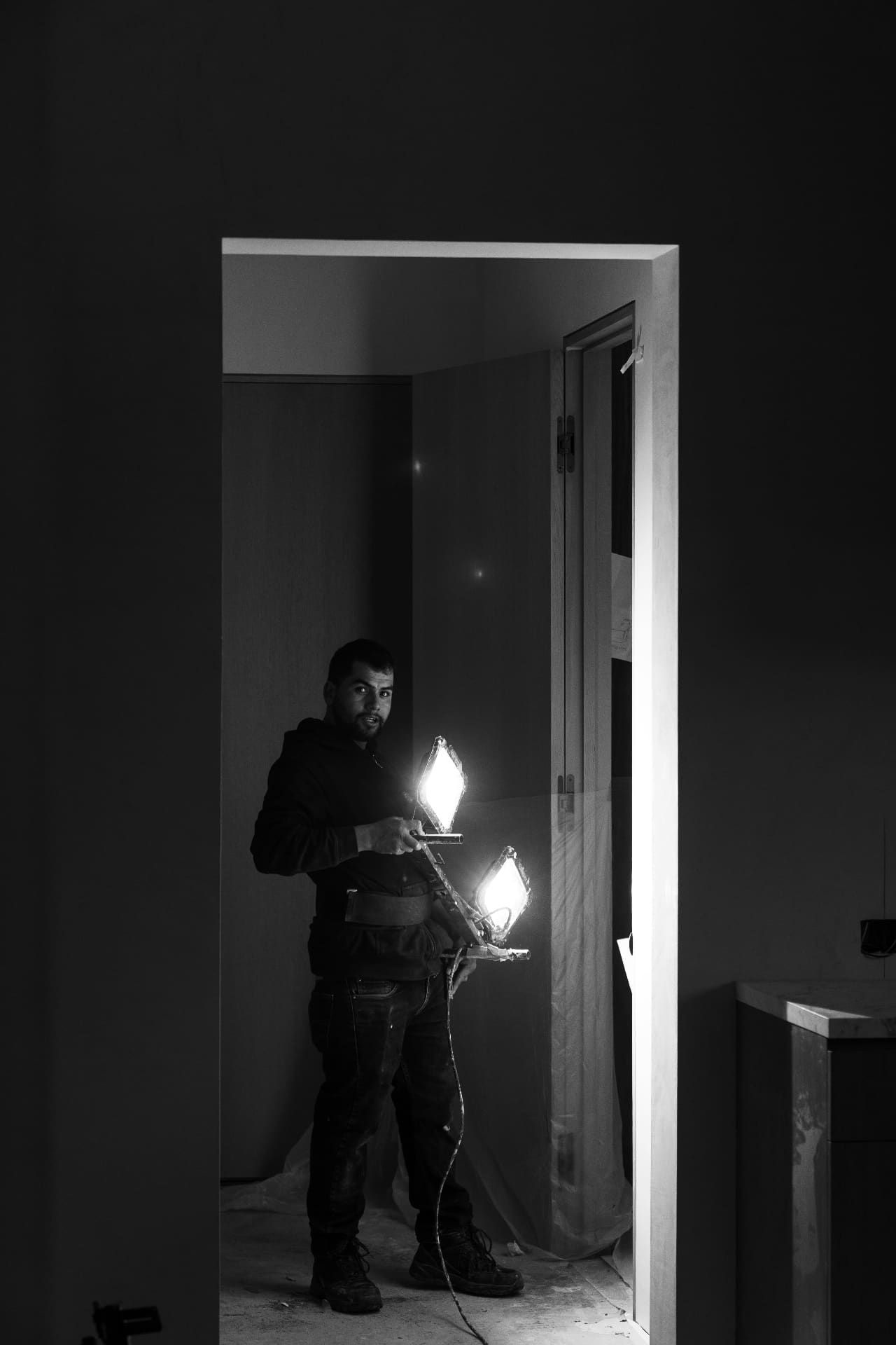 Worker carrying light fixtures through doorway